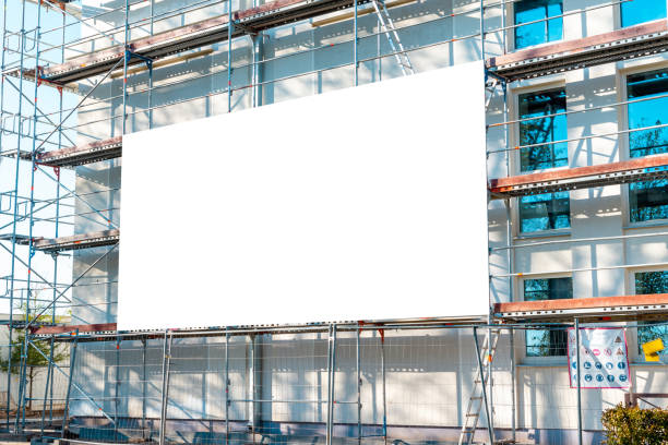 istock Blank white advertisement hanging on the scaffolding of modern building under construction.Reconstruction of a building with white billboard. 1490858891