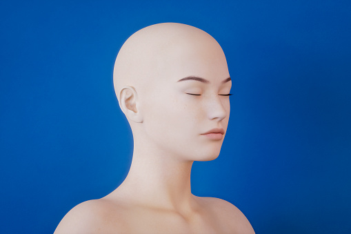A mannequin head attached to a tripod. Isolated on a gray background with copy space.