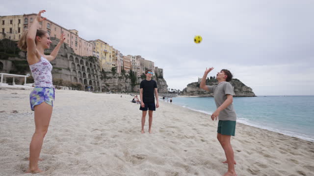 Teenage kids enjoying playing with ball on a beach in Tropea