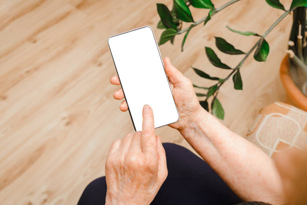 istock Senior woman hands holding smart phone with mockup white blank display,empty screen for social media app ads at home.woman hand texting.Mobile applications technology concept.empty space for advertise 1490874866