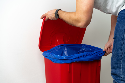 A man changes garbage bag in a bucket close up photo