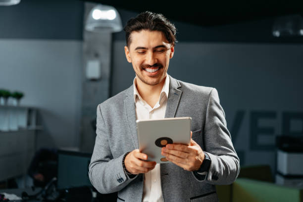 istock Young successful businessman working on digital tablet while standing in office 1490875123