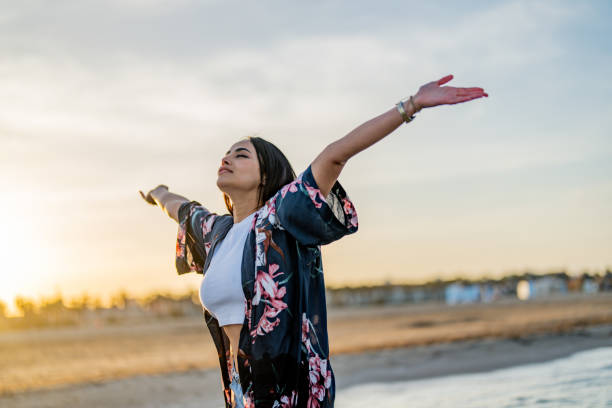 istock Woman standing with arms outstretched on beach 1490881772