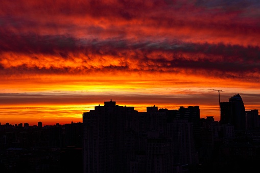 A beautiful view of a sunset in a cityscape, with orange clouds over buildings in the background.