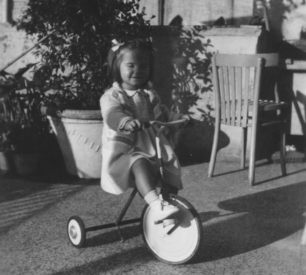 Baby girl cycling on terrace in 1950.