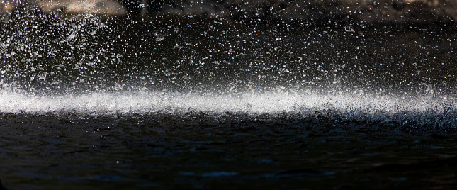 Stopped motion of splashing waterfall drop on pond with dark scene inside cave in tropical rainforest.