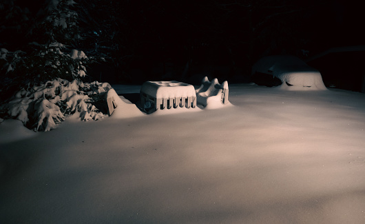 Snowy bench made of pallets at dark night