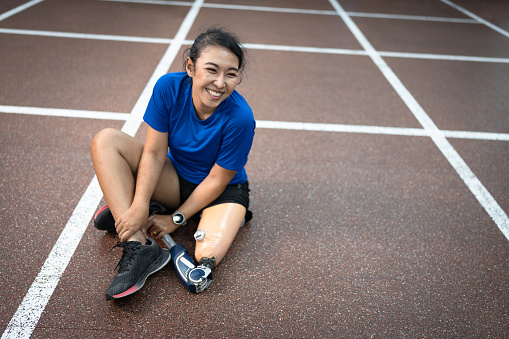 Happy Asia woman with prosthetic leg exercise at gym or fitness