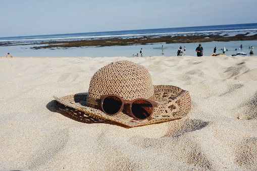 Straw hat and sunglasses on the beach white sand