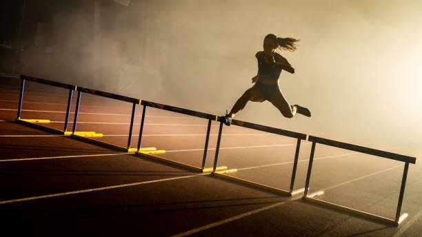 ハードルを飛び越える女性のシルエット - sports track track and field stadium sport night ストックフォトと画像