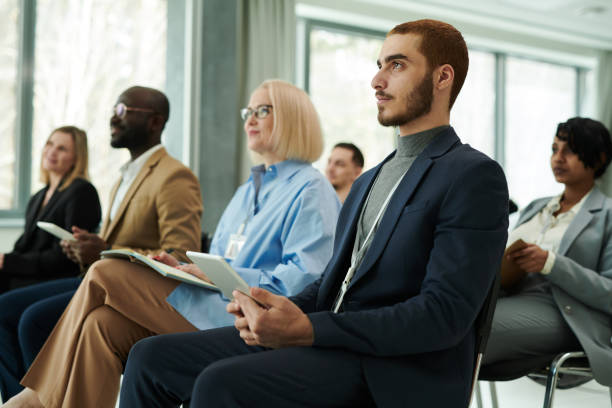 istock Young serious businessman using tablet while listening to lecture 1490896312