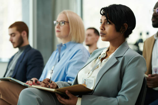 istock Young serious female manager or delegate in formalwear looking at speaker 1490896336