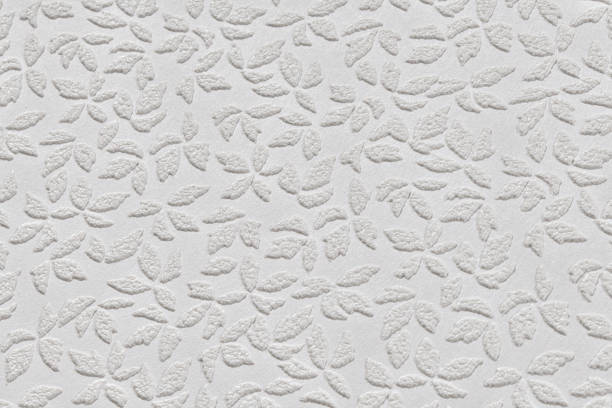 istock White paper wallpaper texture with abstract floral repeating pattern close up. Plastered embossed wall. 1490896463
