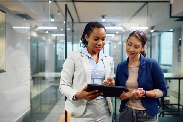 istock Smiling businesswomen cooperating while using touchpad in the office. 1490897867