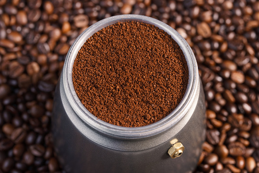 A coffee pot placed on roasted coffee beans