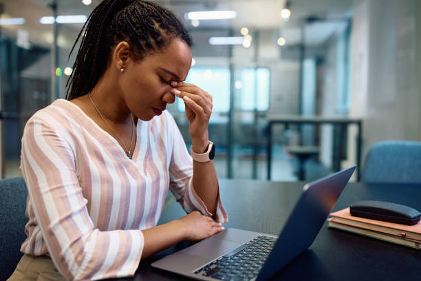 istock Black businesswoman having a headache while working on laptop in the office. 1490901135
