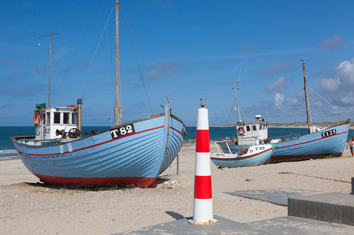 Stenbjerg,Denmark-August 15,2018: Fishing boats on the beach. Stenbjerg is a fishing village on the former island of Thy in the northwest of Jutland. It is noted for its small white fishermens huts next to the sandy beach.
