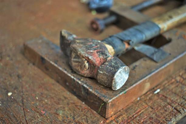 istock Old hammer with a wooden handle wrapped with electrical tape on the master's desktop. 1490909401