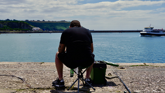 Plymouth, Devon England July 6th 2022: A man fishing at Plymouth harbour.