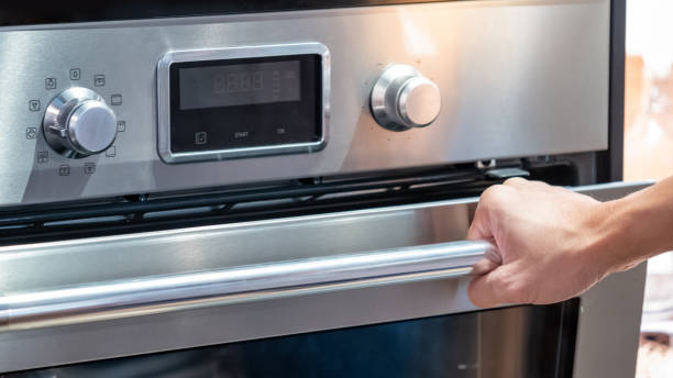istock Male hand pulling oven door handle in modern kitchen. Cooking appliance for domestic kitchen. 1490912028