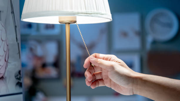 buying lighting equipment concept. male hand pulling light switch chain on white lamp in home decor store. - in en uitschakelen stockfoto's en -beelden