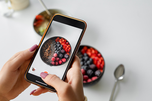 Woman taking photo of smoothie bowl with smartphone