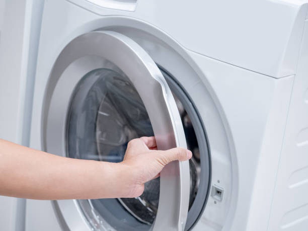 istock Male hand opening automatic washing machine door in laundry room. 1490915350