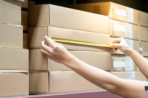 istock Male worker hands using tape measure on carton box in warehouse. Checking dimensions for goods delivery. Logistics service and cargo shipping business concepts 1490915686