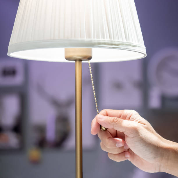 istock Buying lighting equipment concept. Male hand pulling light switch chain on white lamp in home decor store. 1490915984
