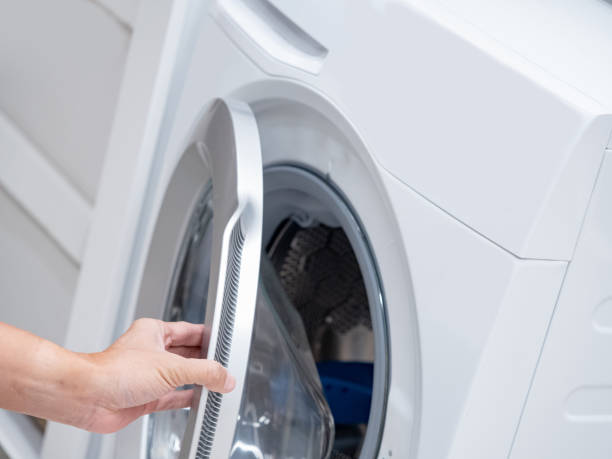 istock Male hand opening automatic washing machine door in laundry room. 1490917612