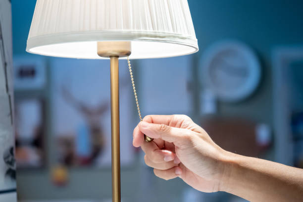 istock Buying lighting equipment concept. Male hand pulling light switch chain on white lamp in home decor store. 1490918452