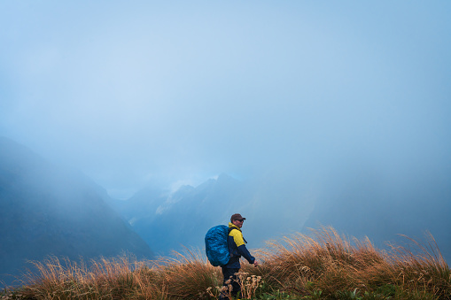 One solo man hiker hiking through Mackinnon Pass, Milford Track, South Island, New Zealand.