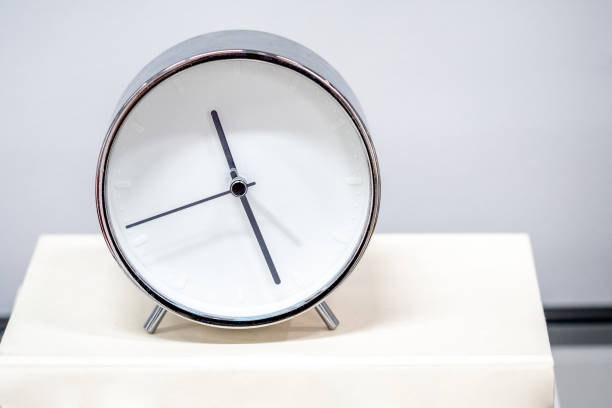 istock Time management concept. Modern silver alarm clock on the book. 1490918657
