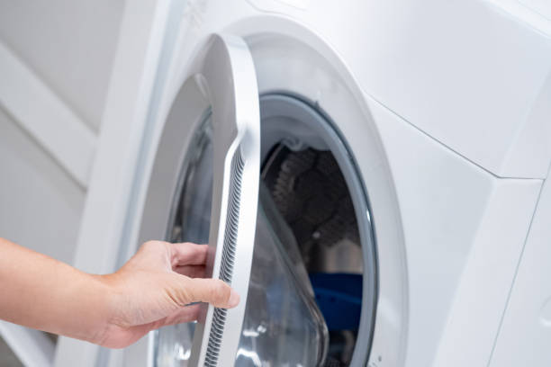 istock Male hand opening automatic washing machine door in laundry room. 1490919366
