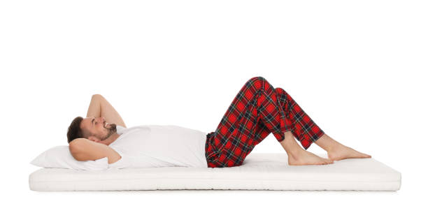 istock Smiling man lying on soft mattress against white background 1490921180
