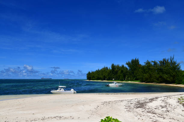 Susupe, Saipan, Commonwealth of the Northern Mariana Islands (CMNI): golden sand beach and small boats - west coast - Battle of Saipan Northern Invasion beaches. Military Sealift Command ships on the horizon.