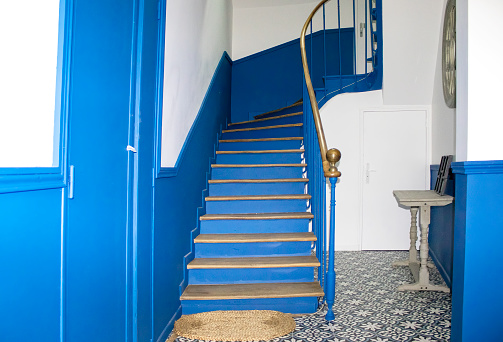 Blue Wooden Staircase Inside a House in France. Entrance Hall in Blue Tones With a Wooden Staircase, a Rustic Table and a Light Rug.