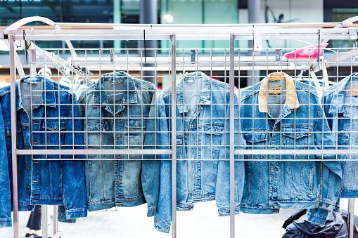 A display of vintage denim jackets for sale at a clothing market.