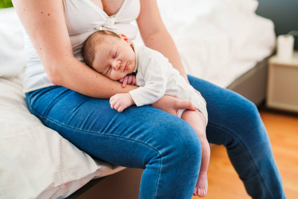 Mother putting her baby to sleep on her lap
