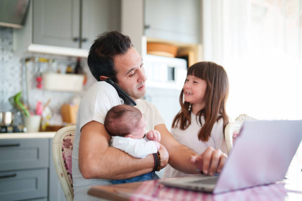 istock Father working on laptop with his two kids in the kitchen 1490927951