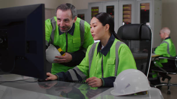 istock Mature foreman in uniform help young asian woman engineer working on computer 1490930383