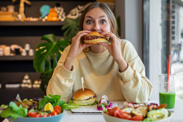 Woman eating vegan burger in cafe