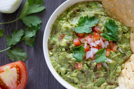 A bowl of guacamole served with plain crackers.