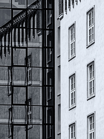 Black and white image of contrast of old and modern architecture with reflection.