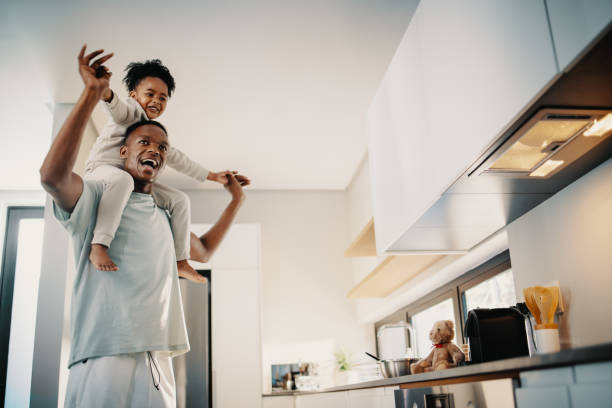 Dad dances with his daughter sitting on his shoulders stock photo