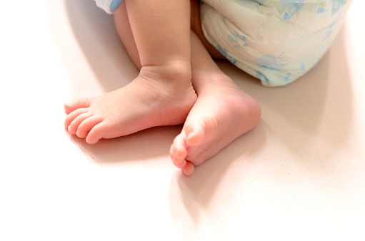 Close-up shot of foot of a newborn Thai girl, 10 days old, wearing a paste lying on a mattress.