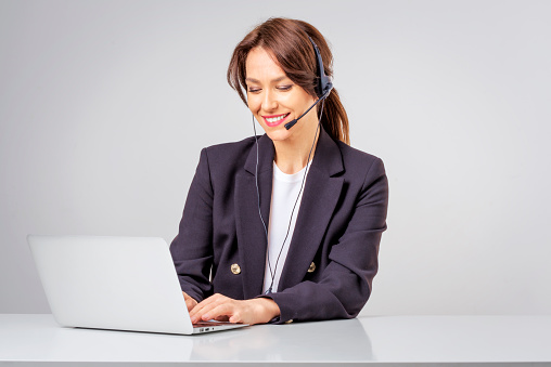 Shot of an attractive businesswoman wearing headsets while working on a computer. Isolated background. Studio shot.