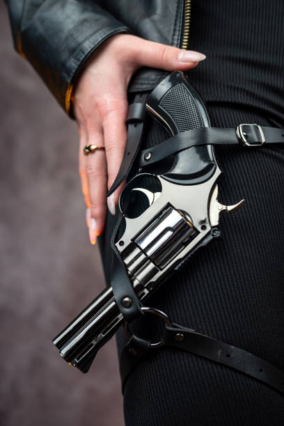 istock slim woman in a black jacket holding gun 1490943108