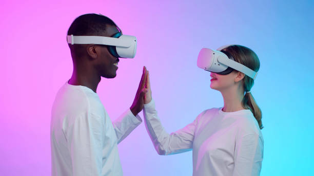istock Virtual future relations. Side view of multiethnic couple in vr goggles touch hands isolated over background. African-American man and caucasian woman in white clothes use augmented reality headset 1490944480