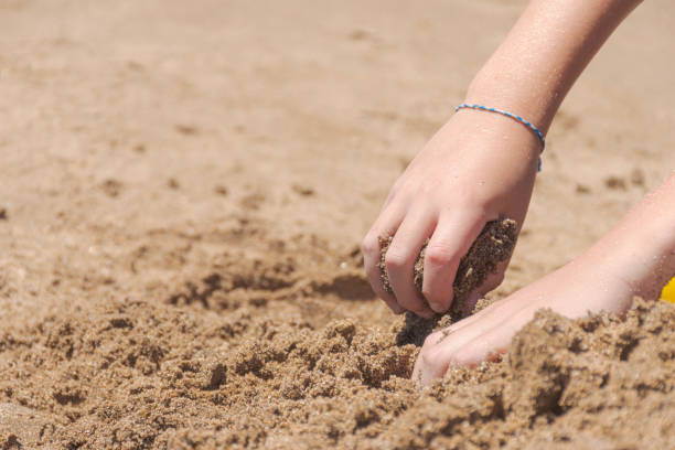 istock Hands of a child playing with sand on the beach. 1490946076